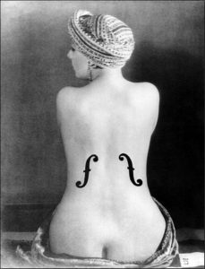 A black-and-white photo of the nude back of a woman with a violin's f-holes