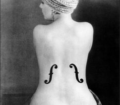 A black-and-white photo of the nude back of a woman with a violin's f-holes