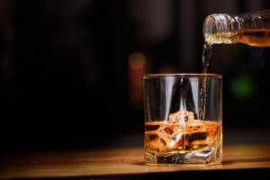 A public domain image of whisky or whiskey being poured into a lowball glass with ice
