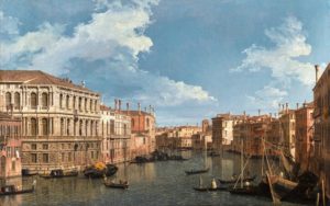 A painting of the Grand Canal in Venice on a partly-cloudy day, showing a number of the city's famous palaces as gondoliers and boatmen ferry their passengers across the water.