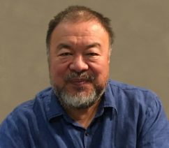 Chinese dissident artist Ai Weiwei in a blue shirt against a beige background