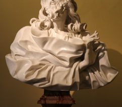 A marble bust of Christ draped in robes and his right hand extended in benediction.