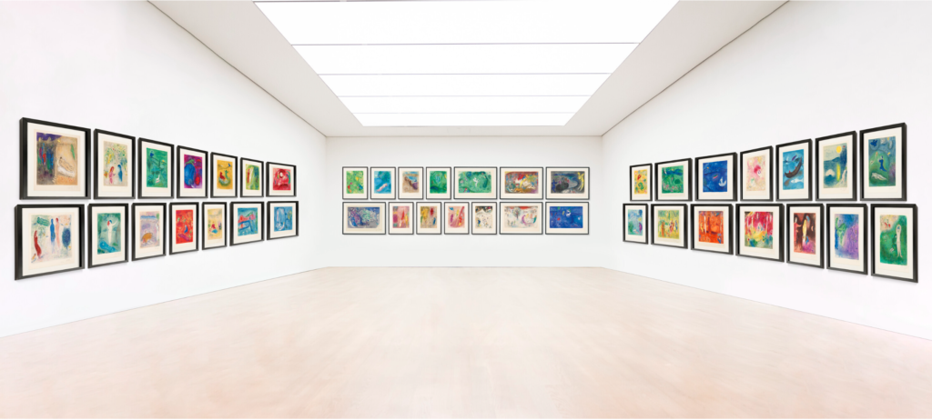 A colorful lithograph series displayed in rows on three walls of a gallery.