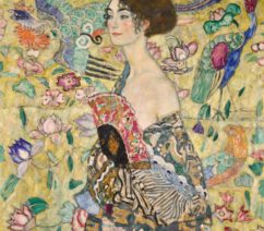 A portrait of a woman in front of an elaborately decorated backdrop. She wears a dressing down slipping off her shoulder, while she hold a fan against her chest.