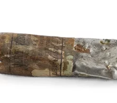 An old, tin paint tube, with the label stained with old paint. The label reads in English, Spanish, and French that it contains emerald green.