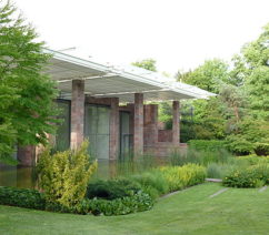 A brick building with a covered patio surrounded by a manicured lawn.