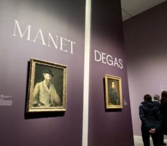 A pair of self-portraits by Manet and Degas on a purple wall at the entrance to the exhibition.