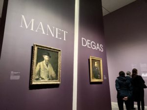 A pair of self-portraits by Manet and Degas on a purple wall at the entrance to the exhibition.