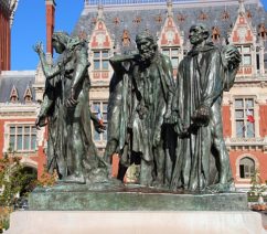 A bronze statue in a public square of six male figures with ropes around their necks