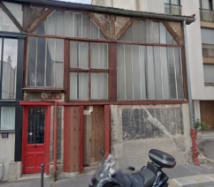 Atelier 11: a three-storey building in Paris with large windows and a red door