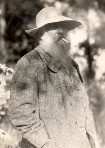A photograph of the painter Claude Monet in his later years, wearing a large-brimmed hat smoking a cigarette.