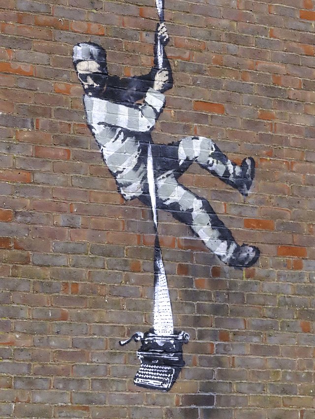 A piece of graffiti showing a prisoner rappelling down a brick wall with a long piece of paper coming from a typewriter.