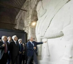 A group of men in suits inspecting a large sculpture