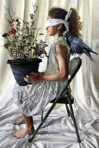 A young girl blindfolded seated on a chair, holding a potted plan and a bird on the back of the chair - Amanda Greive