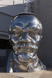 A stainless steel bust of Vladimir Lenin with a small figure of Mao Zedong balancing on top.