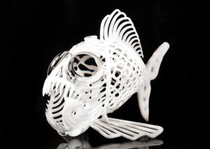 An intricate glass sculpture of a fish with large, magnifying glass eyes and sharp teeth