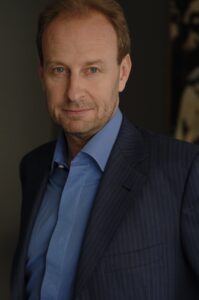 A half-length photograph portrait of a middle-aged Caucasian man in a suit.