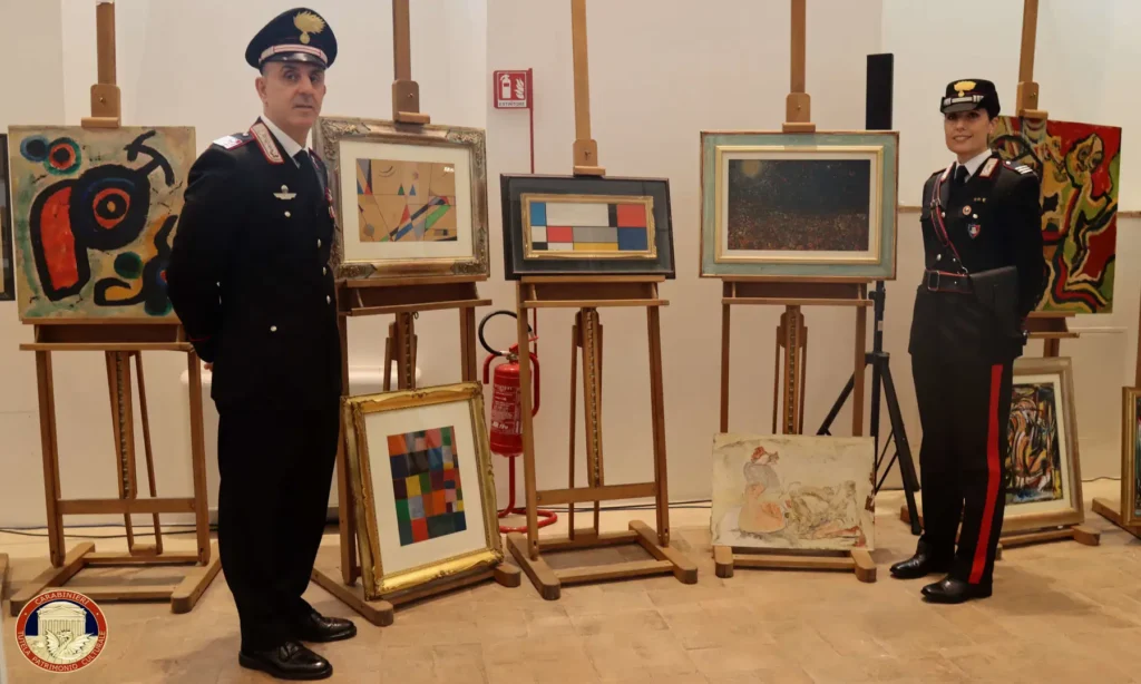 A pair of Italian police officers posing beside easels with forged paintings,