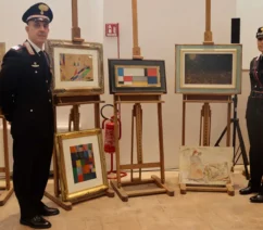 A pair of Italian police officers posing beside easels with forged paintings,