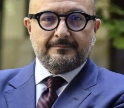 A bald man in a blue suit and glasses