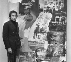 A photo of Robert Rauschenberg standing next to one of his paintings.
