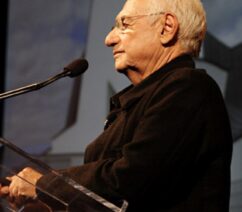 An older man at a podium viewed in profile.