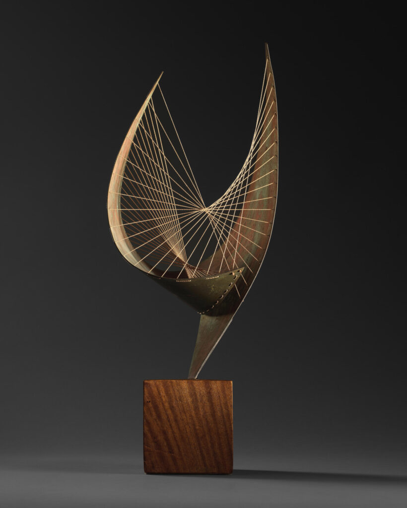 A sculpture of metal pieces curled into wing-like shapes decorated with strings,