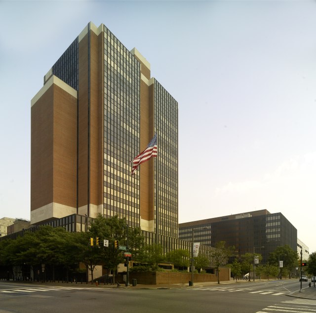 A large brick and glass building with an American flag out front.