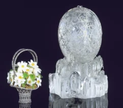 An egg made of crystal alongside a small sculpture of a bouquet.