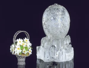 An egg made of crystal alongside a small sculpture of a bouquet.