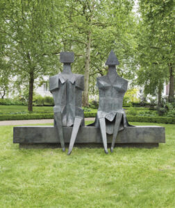 A bronze sculpture of two bronze figures sitting on a bench.