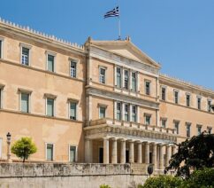 The facade of a building flying the Greek flag.