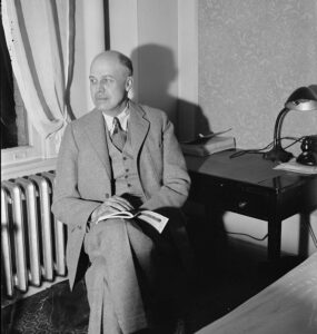 A black-and-white photograph of the painter Edward Hopper, seated.