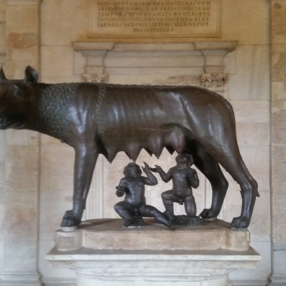 bronze of an animal and two people underneath her.