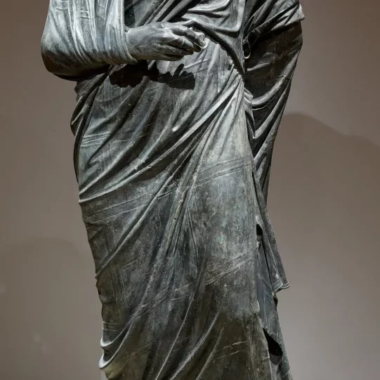 A headless ancient Roman bronze statue of a man in a toga formerly held by the Cleveland Museum of Art.