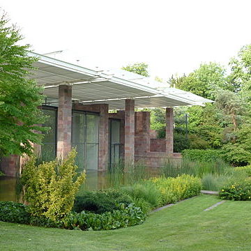 A brick building with a covered patio surrounded by a manicured lawn.