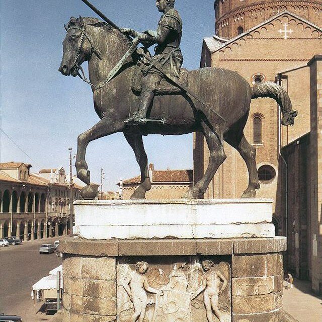 A large bronze statue of a man on horseback in front of a cathedral in Italy.