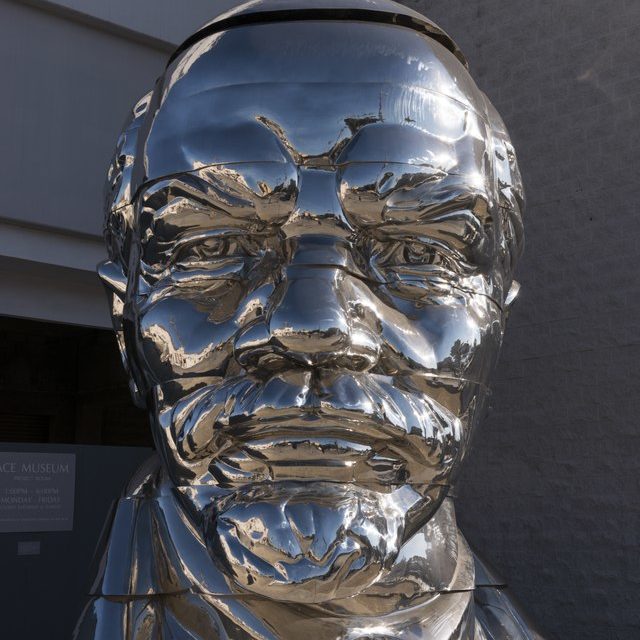 A stainless steel bust of Vladimir Lenin with a small figure of Mao Zedong balancing on top.