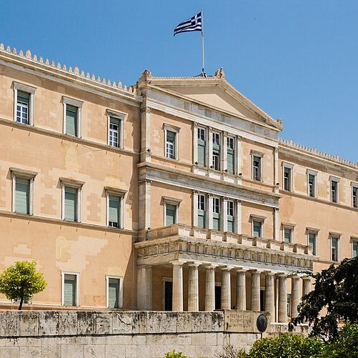 The facade of a building flying the Greek flag.