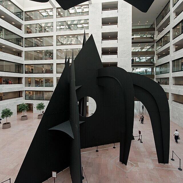 A large black metal sculpture in the atrium of an office building.