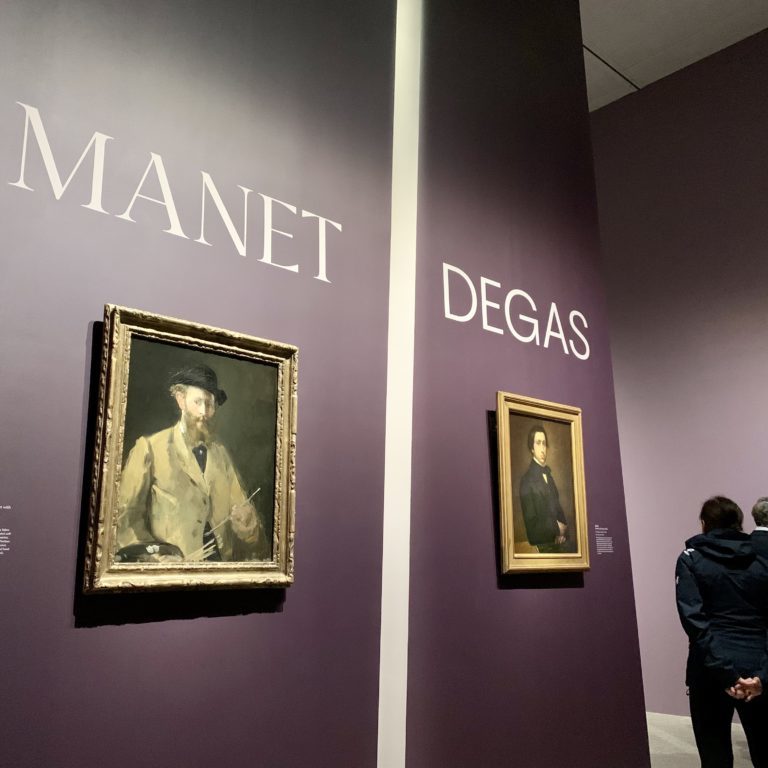 A pair of self-portraits by Manet and Degas on a purple wall at the entrance to the exhibition.