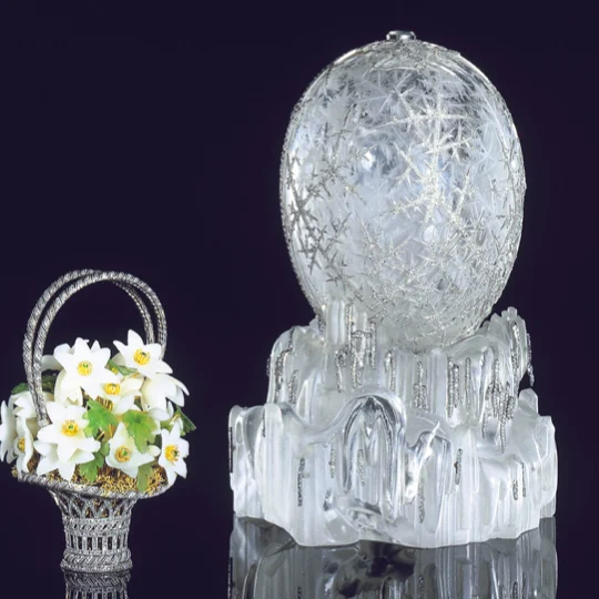 An egg made of crystal alongside a small sculpture of a bouquet.