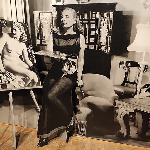 A black-and-white cutout of the artist Tamara de Lempicka shown against a black-and-white display and an easel