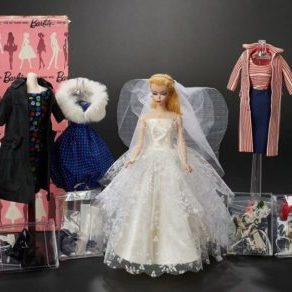 #1 Barbie doll in wedding dress with other clothing and accessories behind her