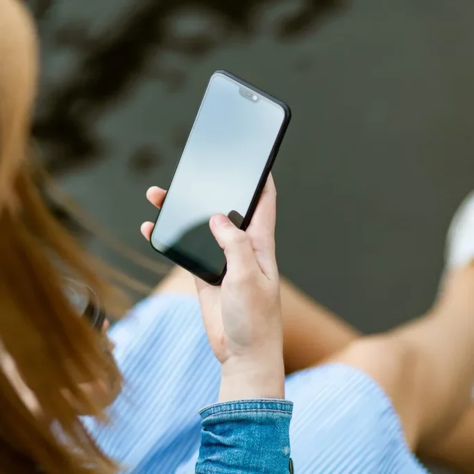A generic photograph of a woman holding a smartphone