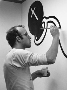 A black-and-white photo of Keith Haring at work
