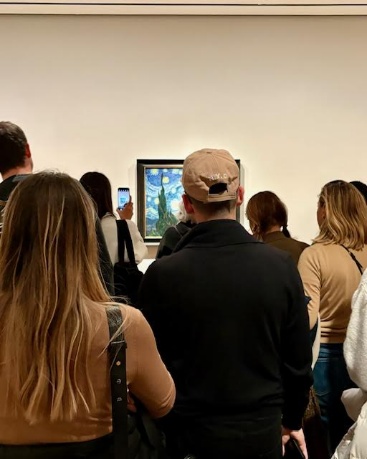 A group of people looking at a paintingDescription automatically generated