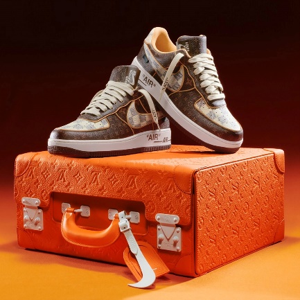 A pair of Louis Vuitton sneakers on top of an orange Louis Vuitton caseDescription automatically generated